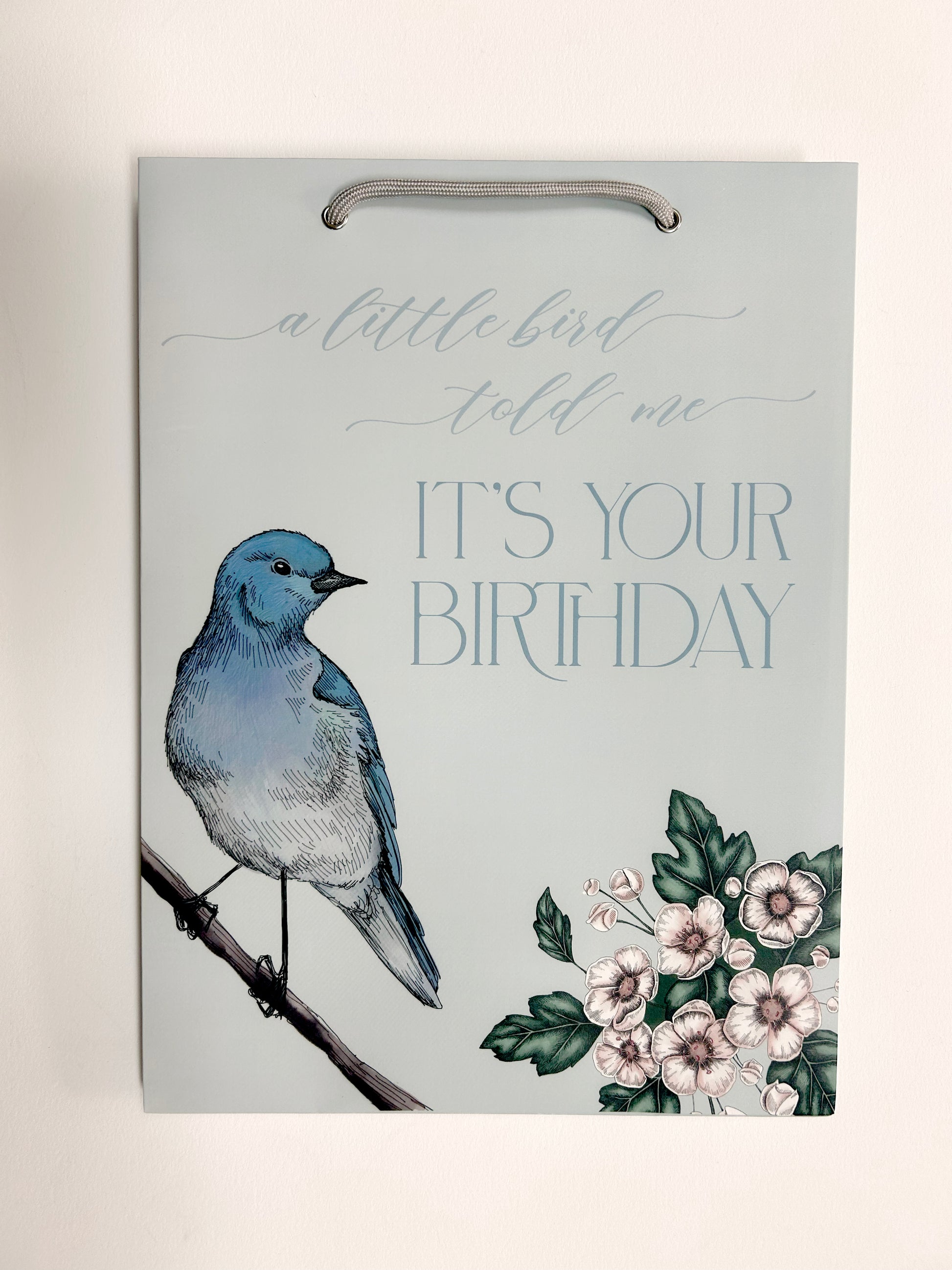 photo of flat blue gift bag with florals that reads "A little bird told me it's your birthday" by Rust Belt Love