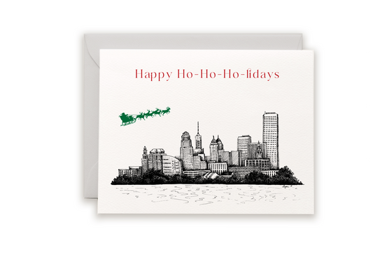 Letterpress card with city skyline and Santa/ reindeer flying over that reads Happy Ho-Ho-Ho-lidays" by Rust Belt Love.