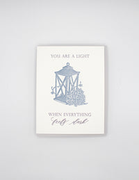 Letterpress love card with a lantern and florals that says " You Are A Light When Everything Feels Dark" By Rust Belt Love