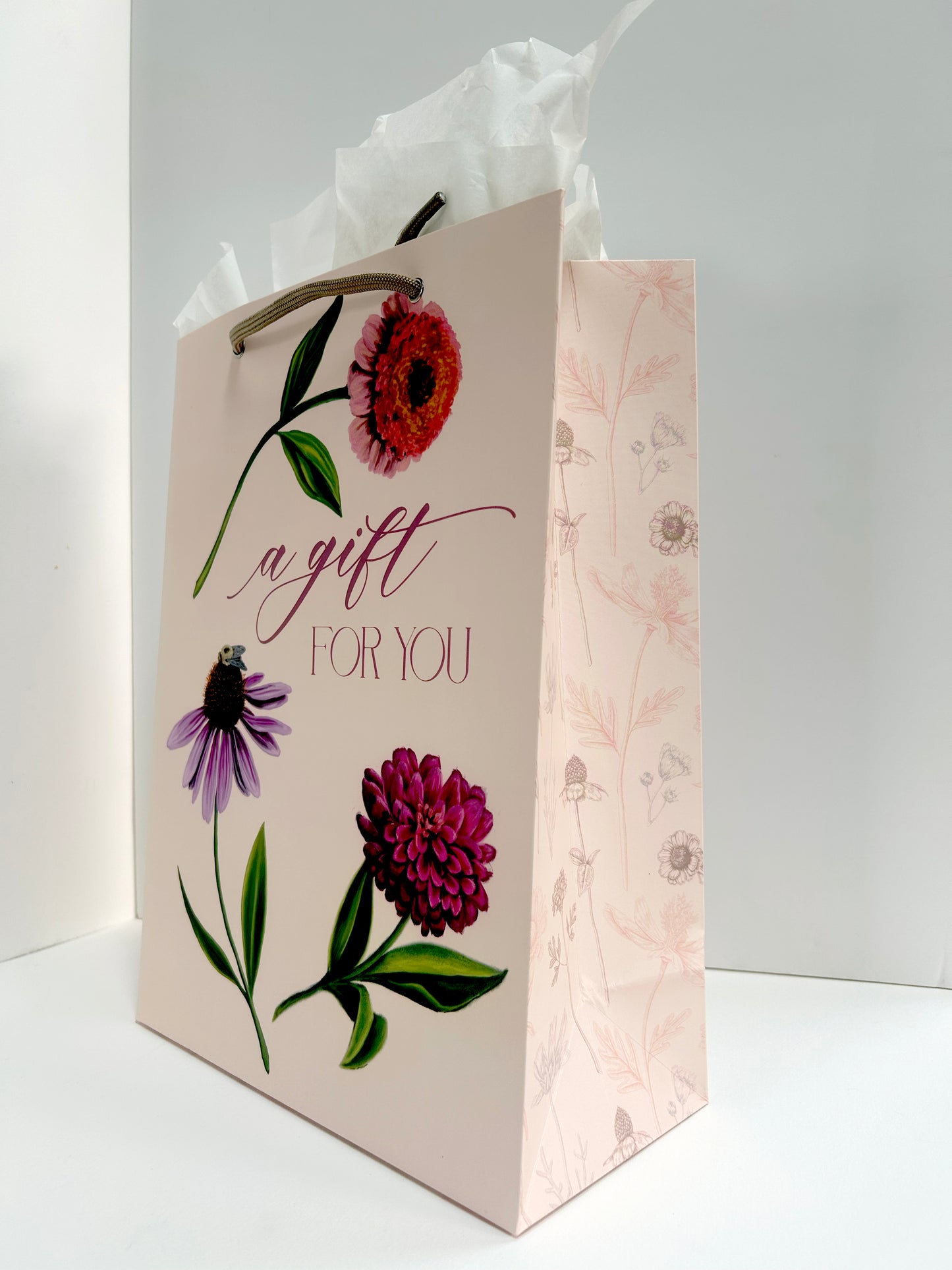 Standing up, angled photo of pink gift bag with florals that reads "A gift for you" by Rust Belt Love