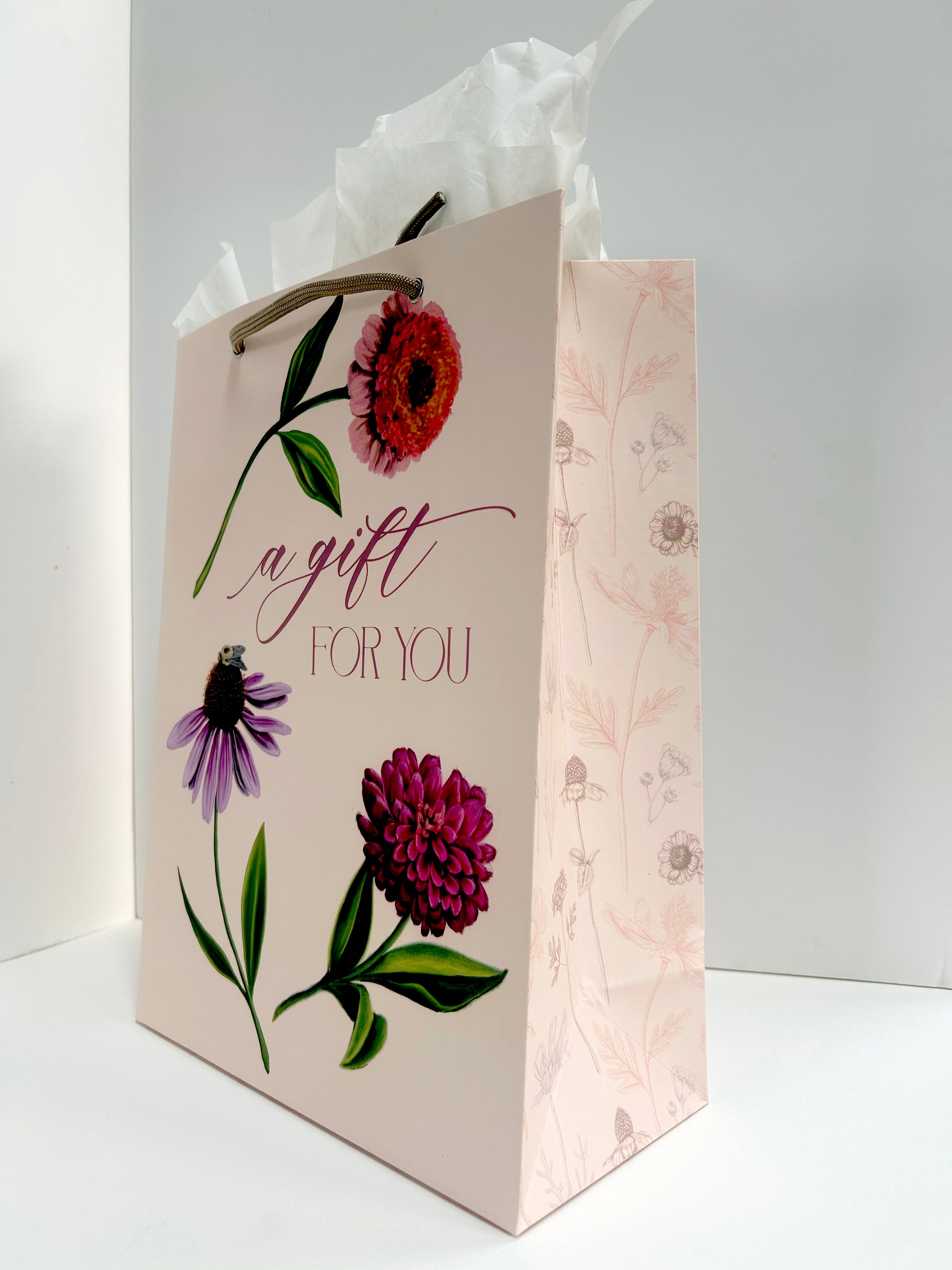 Standing up, angled photo of pink gift bag with florals that reads "A gift for you" by Rust Belt Love