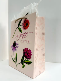 Standing up, angled photo of pink gift bag with florals that reads "A gift for you" by Rust Belt Love