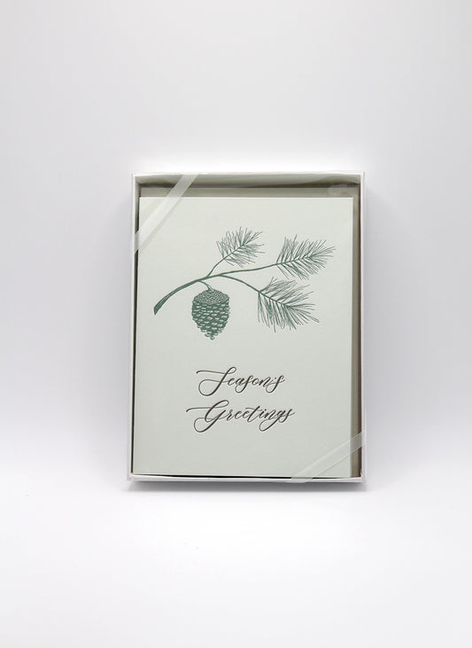 Box of green letterpress holiday cards with branch and pinecone that reads "Season's Greetings" by Rust Belt Love