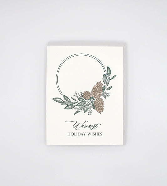 Box of letterpress holiday cards with pinecones and greenery that says "Warmest holiday wishes" by Rust Belt Love