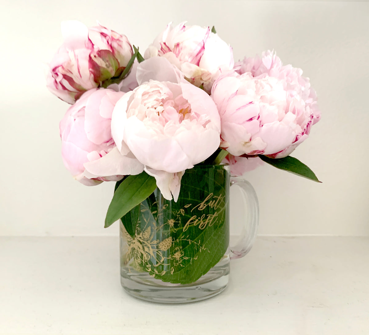 Gold ink on clear glass mug with flowers and that says "but first..." by In Good Company